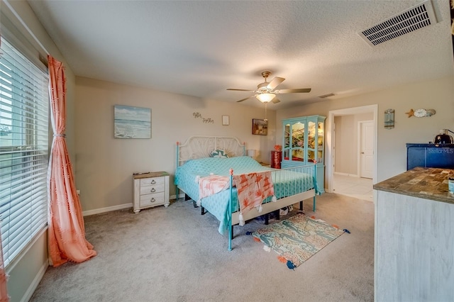 bedroom with a textured ceiling, ceiling fan, and light carpet