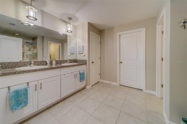 bathroom with tile patterned flooring, a textured ceiling, a shower, and vanity