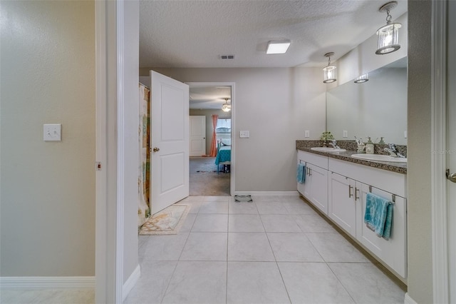 bathroom with a textured ceiling, tile patterned flooring, and vanity