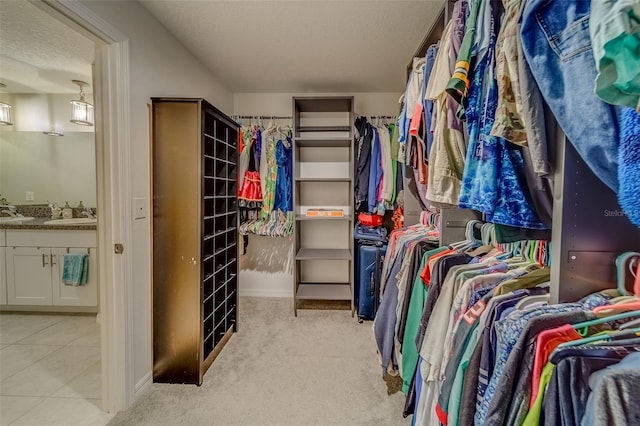 walk in closet with light colored carpet and sink