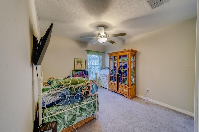 carpeted bedroom featuring ceiling fan and a textured ceiling