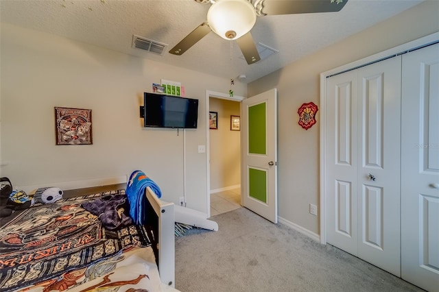 carpeted bedroom featuring a closet, ceiling fan, and a textured ceiling