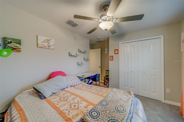 carpeted bedroom with a textured ceiling, ceiling fan, and a closet