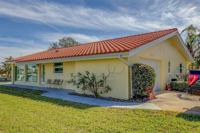 back of property featuring a garage and a lawn