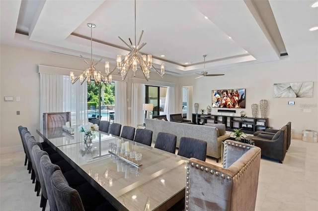 dining area featuring ceiling fan with notable chandelier and a tray ceiling