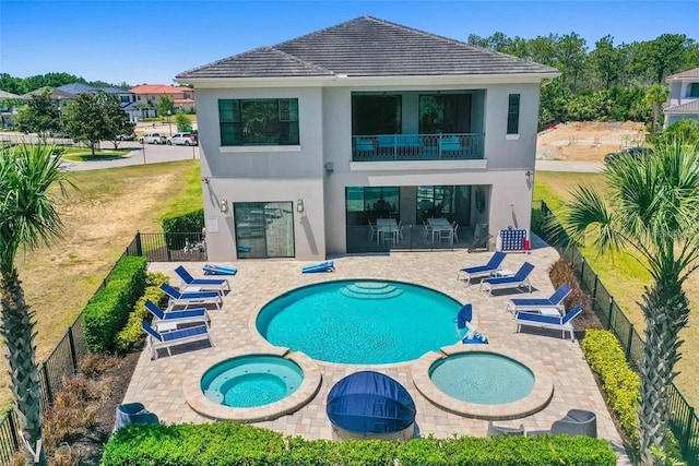 back of house featuring a patio area, a balcony, and a swimming pool with hot tub