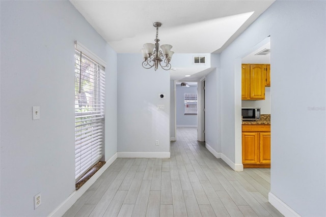 unfurnished dining area with a chandelier and light hardwood / wood-style floors