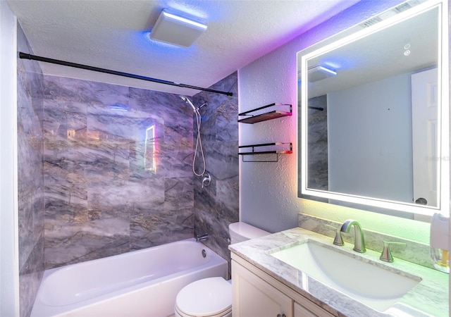 full bathroom with toilet, vanity, a textured ceiling, and tiled shower / bath