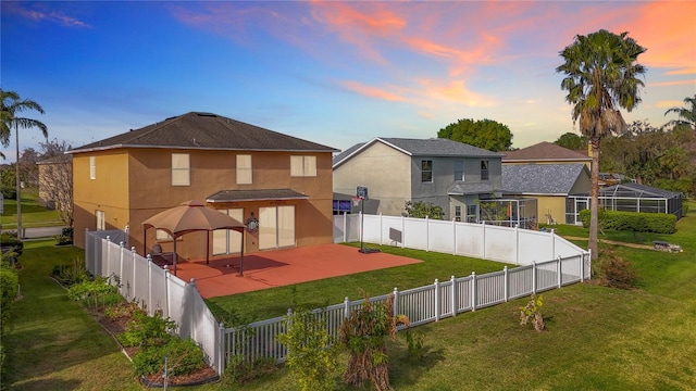 rear view of house with a fenced backyard, a lawn, a patio, and stucco siding