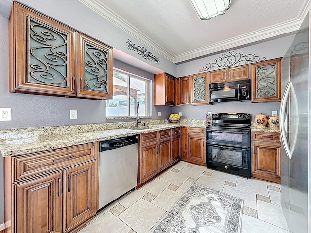 kitchen with light stone counters, brown cabinets, crown molding, black appliances, and a sink