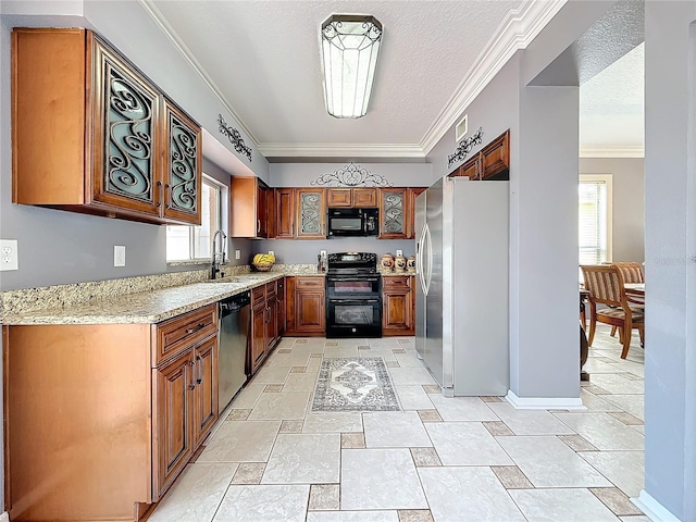 kitchen with brown cabinetry, ornamental molding, light stone countertops, black appliances, and a sink