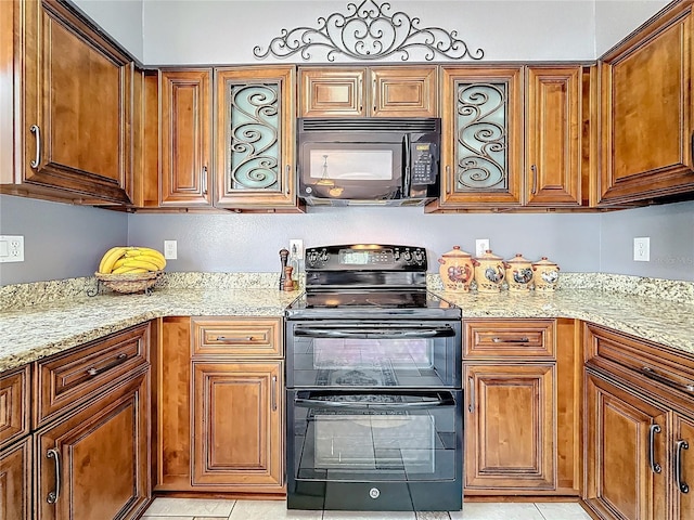 kitchen featuring light stone countertops, black appliances, light tile patterned floors, and brown cabinets