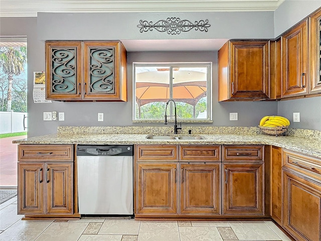 kitchen with brown cabinets, a sink, stainless steel dishwasher, and light stone countertops