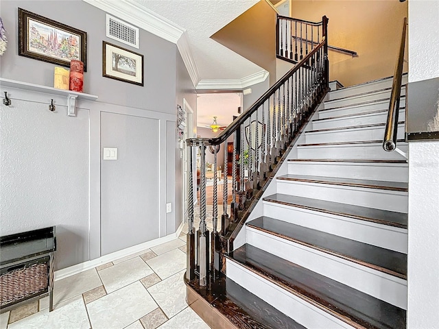 stairs with visible vents, wainscoting, a textured ceiling, crown molding, and a decorative wall