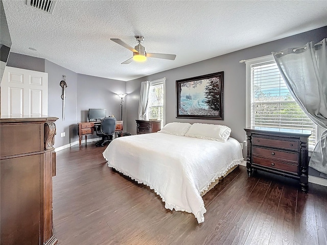 bedroom with visible vents, dark wood finished floors, a textured ceiling, and multiple windows