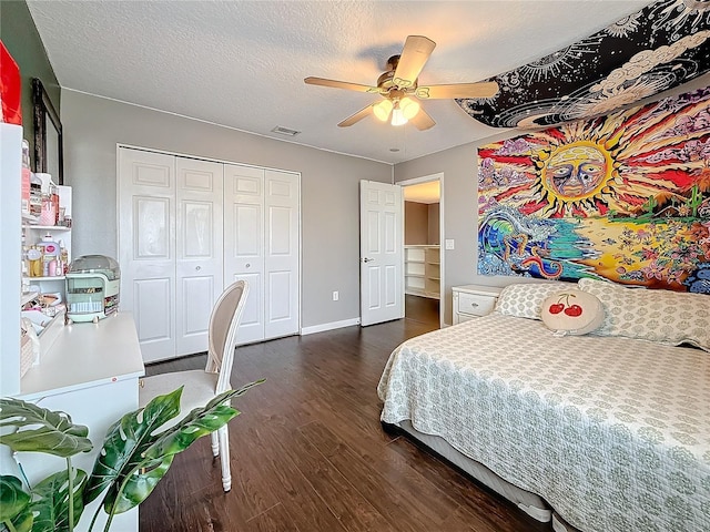 bedroom featuring dark wood-style floors, a closet, visible vents, ceiling fan, and a textured ceiling