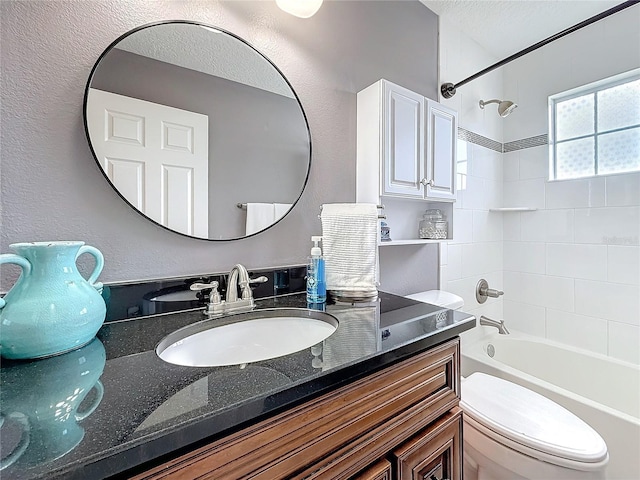 bathroom featuring shower / bath combination, a textured wall, vanity, and toilet