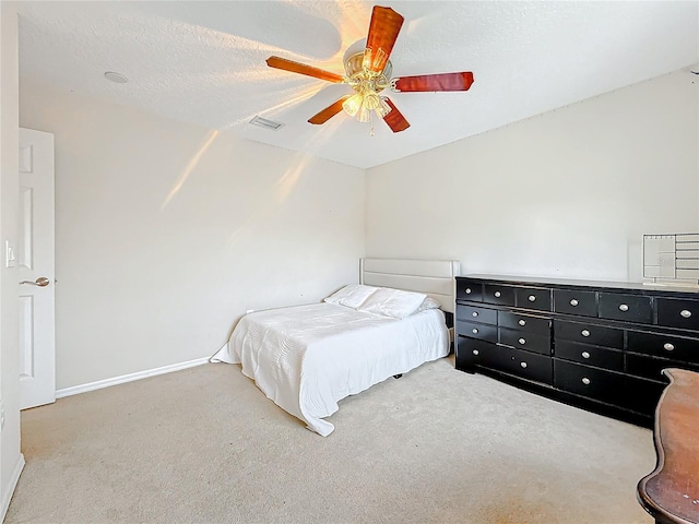 carpeted bedroom featuring a ceiling fan, visible vents, baseboards, and a textured ceiling