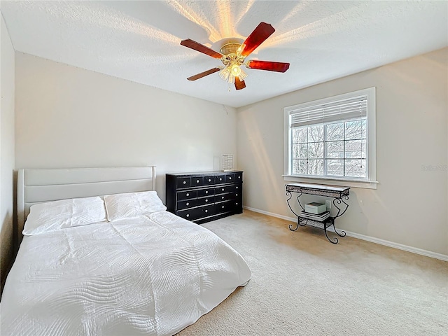 carpeted bedroom with ceiling fan, baseboards, and a textured ceiling