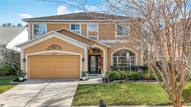 traditional-style house with a garage, driveway, a front yard, and stucco siding