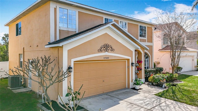 view of front facade featuring a garage, concrete driveway, stucco siding, and cooling unit