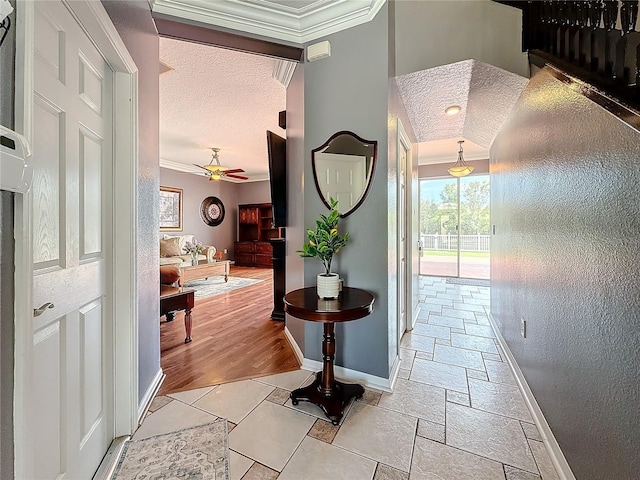 hallway featuring a textured ceiling, baseboards, ornamental molding, and plenty of natural light