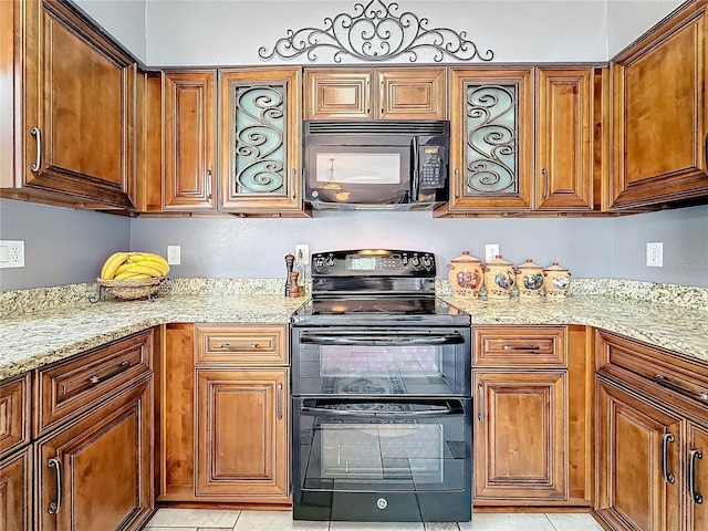 kitchen with brown cabinets, black appliances, and light stone countertops