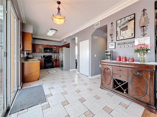 kitchen with visible vents, freestanding refrigerator, crown molding, black microwave, and range