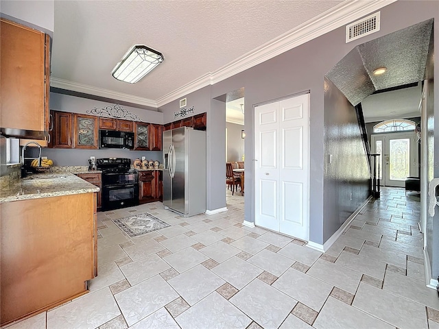 kitchen featuring visible vents, ornamental molding, baseboards, a sink, and black appliances