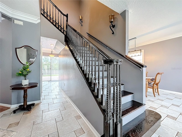 staircase with a textured ceiling, baseboards, ornamental molding, and stone tile flooring