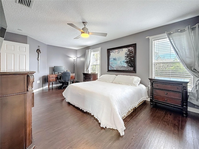 bedroom with ceiling fan, a textured ceiling, visible vents, baseboards, and dark wood-type flooring