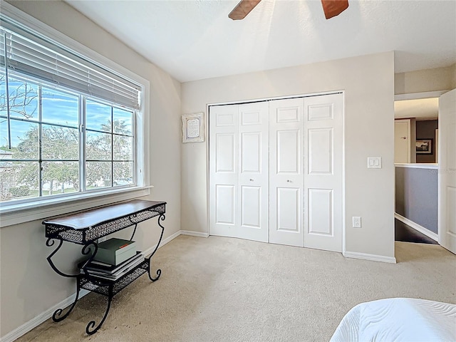 bedroom with a closet, baseboards, a ceiling fan, and carpet flooring