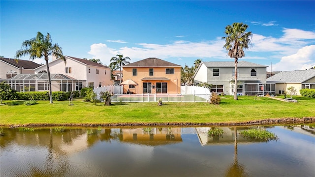 rear view of property featuring a water view, a fenced backyard, a yard, and a residential view