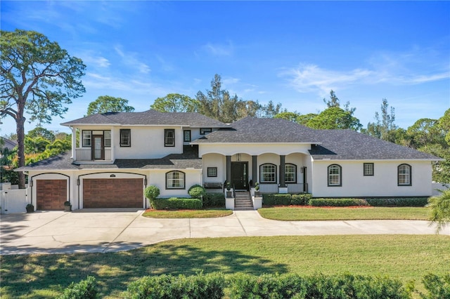 view of front of house with a front yard, covered porch, and a garage