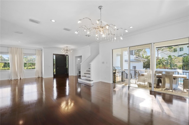 foyer entrance with wood-type flooring, ornamental molding, and a chandelier