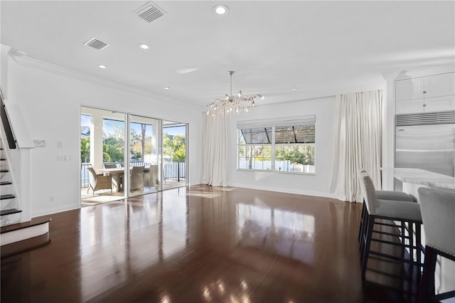 living room featuring dark hardwood / wood-style floors, crown molding, and an inviting chandelier