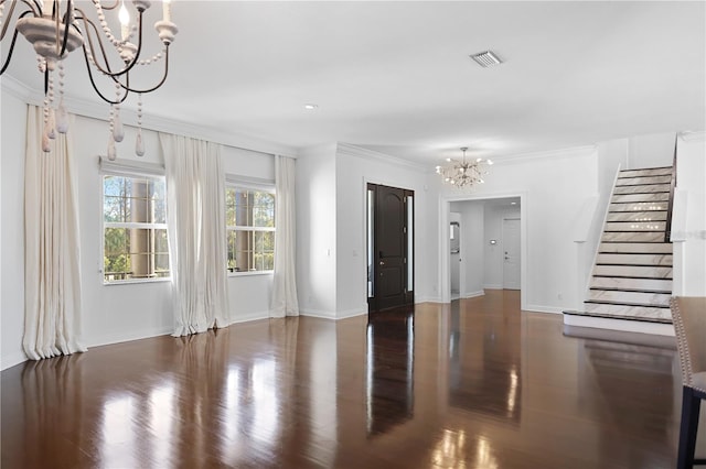 unfurnished living room with dark hardwood / wood-style flooring, crown molding, and a chandelier