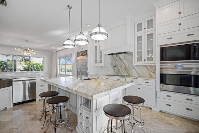 kitchen featuring backsplash, a center island with sink, black appliances, sink, and a kitchen breakfast bar