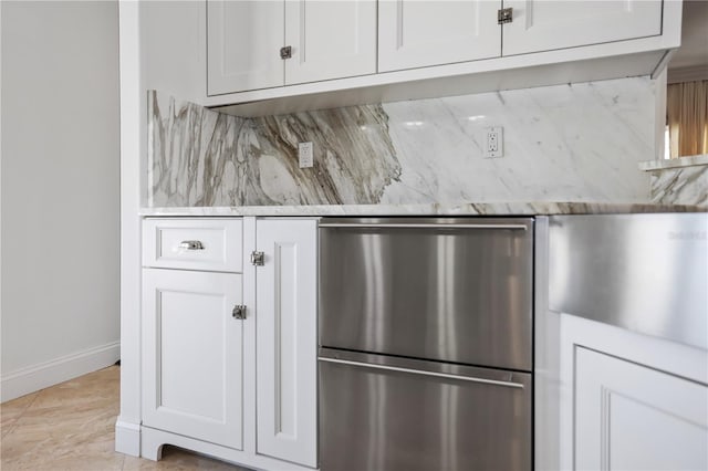 kitchen featuring light tile patterned floors, backsplash, stainless steel fridge, and white cabinetry