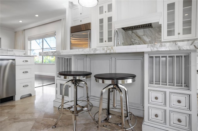 kitchen with white cabinets, backsplash, light stone counters, and stainless steel appliances