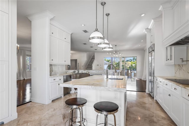 kitchen with a kitchen bar, stainless steel appliances, tasteful backsplash, an island with sink, and sink