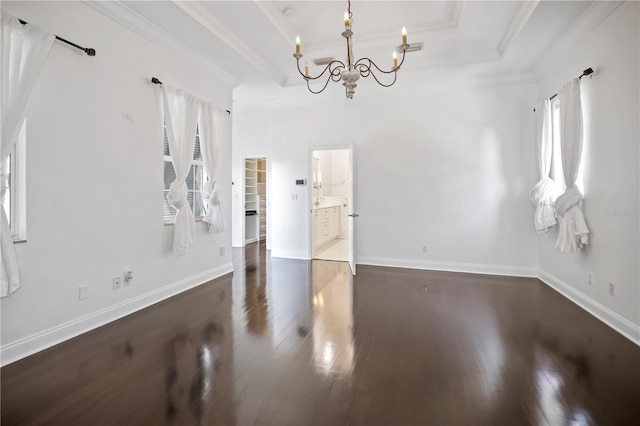 spare room featuring a healthy amount of sunlight, dark wood-type flooring, and an inviting chandelier