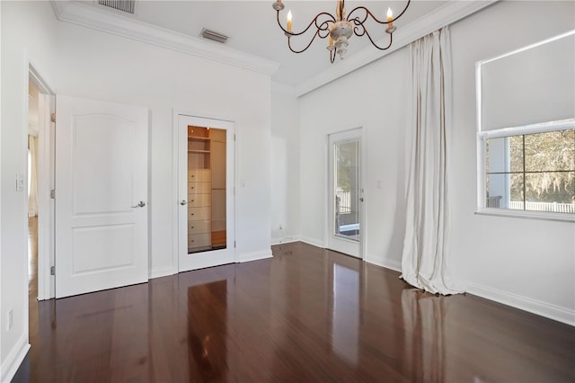 spare room featuring dark wood-type flooring, a notable chandelier, and crown molding