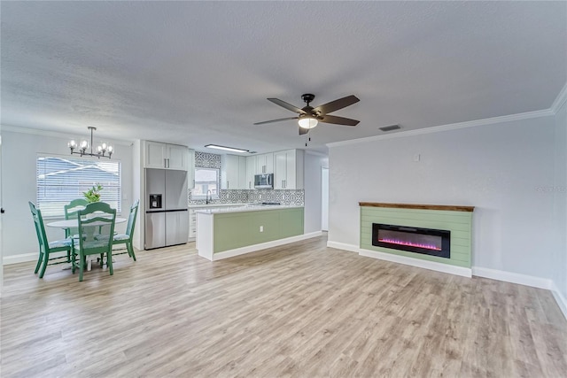 unfurnished living room featuring ceiling fan with notable chandelier, a textured ceiling, light hardwood / wood-style floors, and crown molding