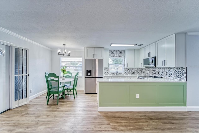 kitchen with stainless steel appliances, white cabinets, decorative light fixtures, tasteful backsplash, and crown molding