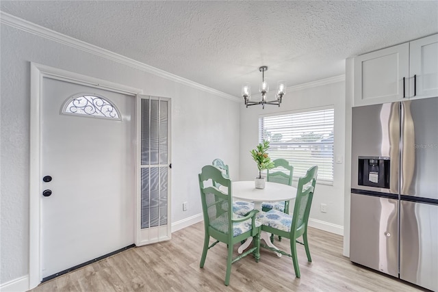 dining space featuring a textured ceiling, an inviting chandelier, light hardwood / wood-style floors, and crown molding