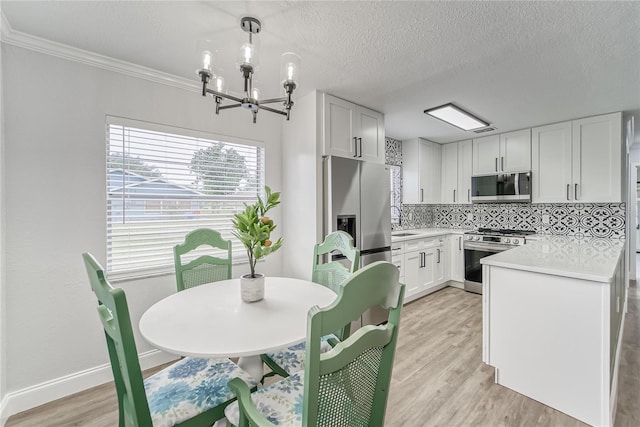 kitchen with decorative light fixtures, tasteful backsplash, white cabinets, appliances with stainless steel finishes, and ornamental molding