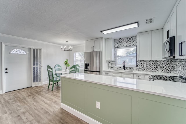 kitchen featuring stainless steel appliances, sink, tasteful backsplash, hanging light fixtures, and a chandelier