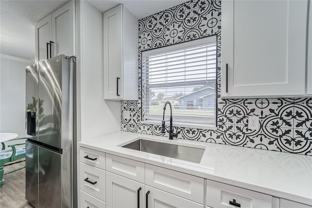 kitchen with sink, white cabinetry, hardwood / wood-style floors, stainless steel fridge, and crown molding