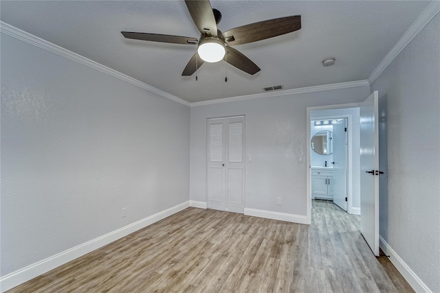 unfurnished bedroom with ceiling fan, light hardwood / wood-style floors, ornamental molding, and a closet